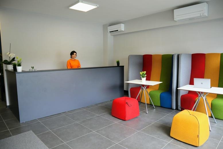 Bright reception area with a grey desk and a colorful rainbow-striped seating banquette.