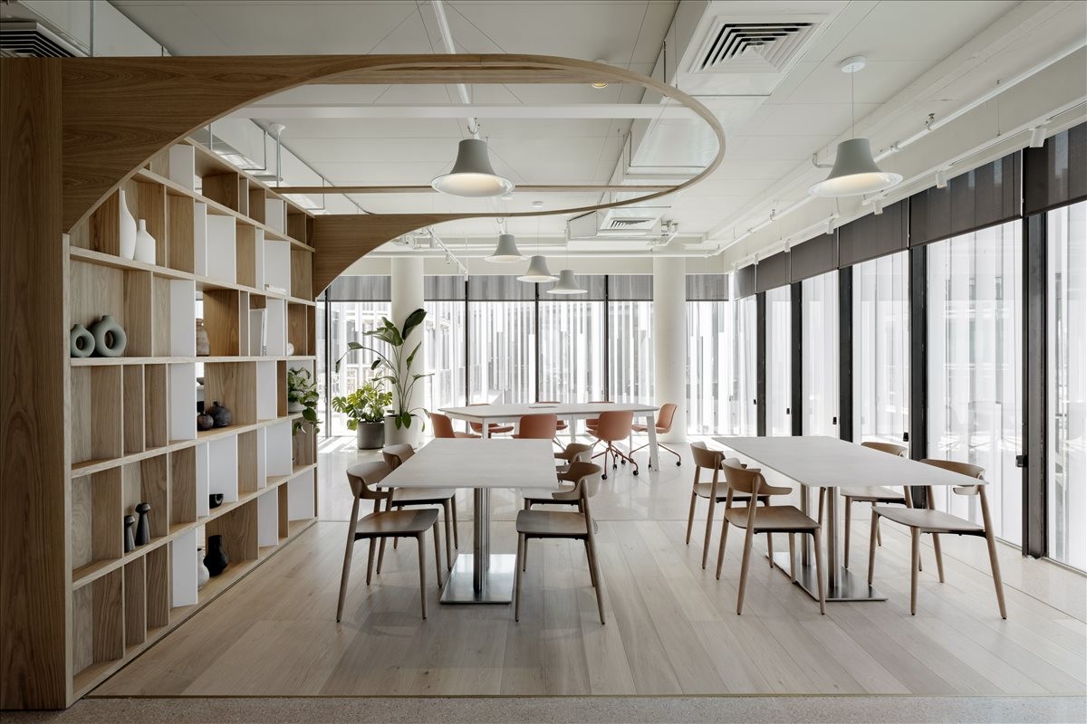 Spacious communal coworking area at HaTamar 3, Even Yehuda with modern wooden shelving and natural light.