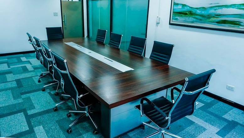 Spacious boardroom with a large dark wood table and blue patterned carpet.
