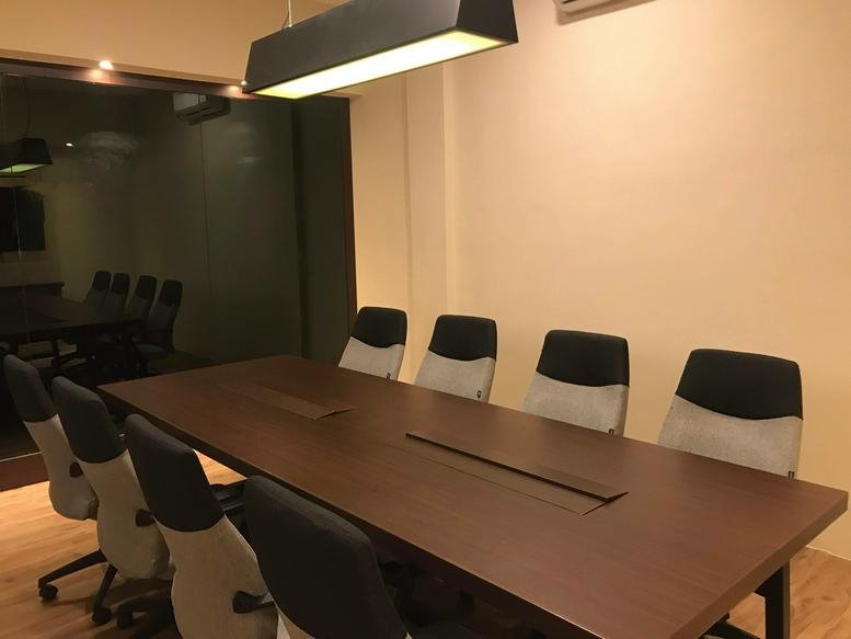 Large boardroom with a long wooden table and grey ergonomic chairs at Jalan Arjuna Utara No. 35.