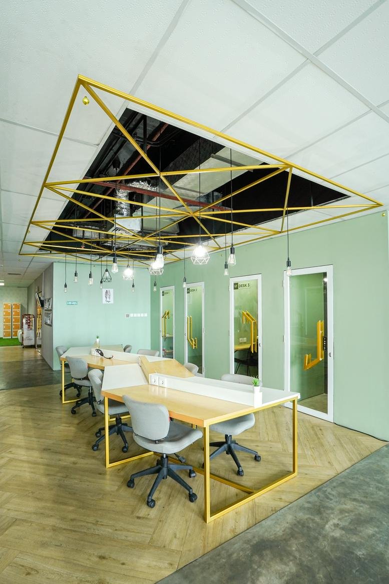 Spacious coworking area at Harton Tower with geometric ceiling art and light green walls.