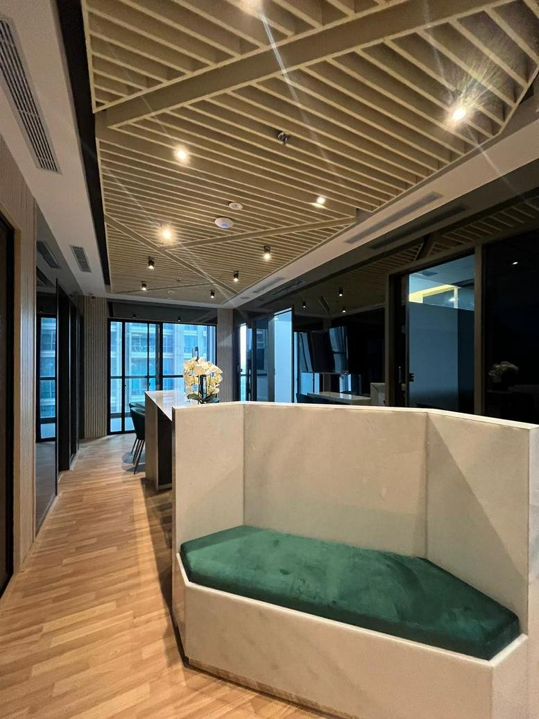Wide-angle view of a common lounge area with wood floors, marble accents, and a distinctive slatted ceiling.