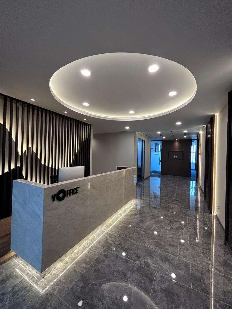 Modern reception area at Atria Tower with a stone desk, circular light fixture, and marble flooring.