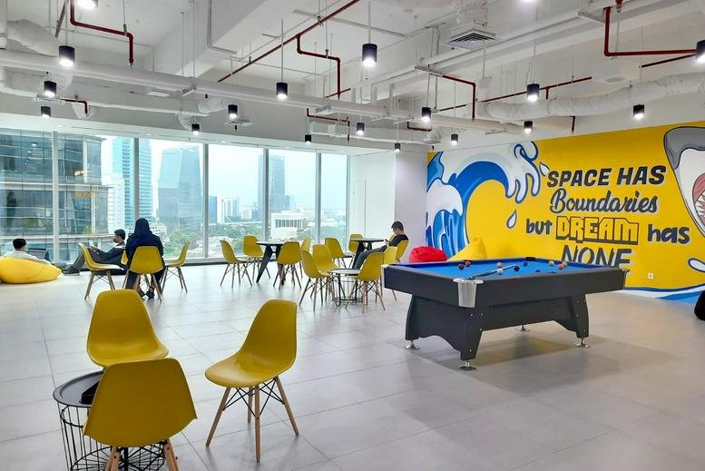 Vibrant communal lounge featuring a pool table, yellow chairs, and a colorful mural.