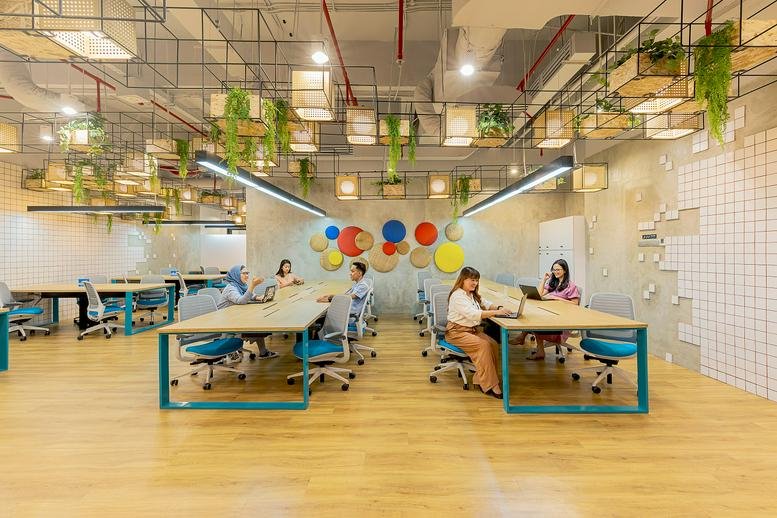 Collaborative coworking space with long wooden tables and hanging greenery.