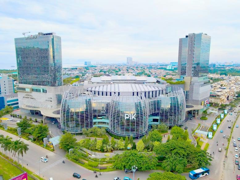 Aerial exterior view of the modern glass-facade building on Pantai Indah Kapuk Street.