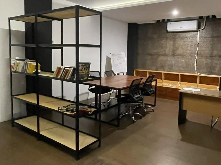 Spacious open workspace at Jl. Arifin No. 89, Kepatihan Kulon featuring wooden desks and industrial shelving.