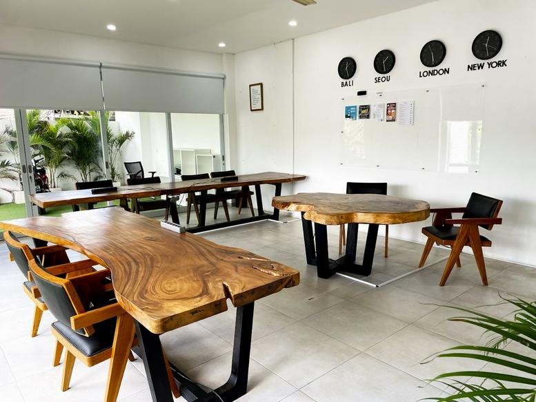 Spacious communal coworking area with live-edge wooden tables and world clocks at Jl. Karang Suwung.