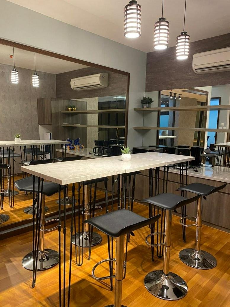 Spacious communal dining area with high tables and wooden floors at Grand Jati Junction Level 3.