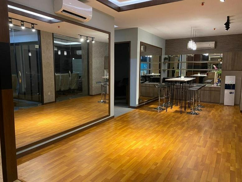 Spacious communal lounge at Grand Jati Junction Level 3 with wood flooring and large mirrors.