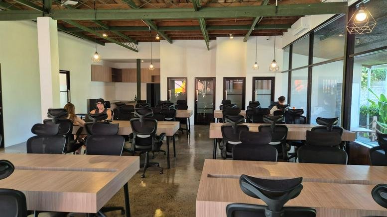 Spacious open-plan workspace at Jl. Raya Tumbakbayuh Gg. Pandan Asri 14 No. Depan with rows of wooden desks
