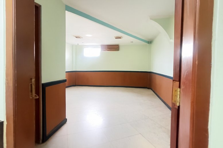 Spacious interior room at Jl. Sri Kuncoro Utara, Gang I No. Kav. 33 featuring light green walls and wood wainscoting.