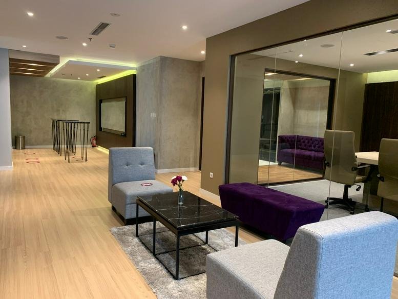 Modern lounge area at Sudirman 7. 8 with grey armchairs and a purple ottoman.