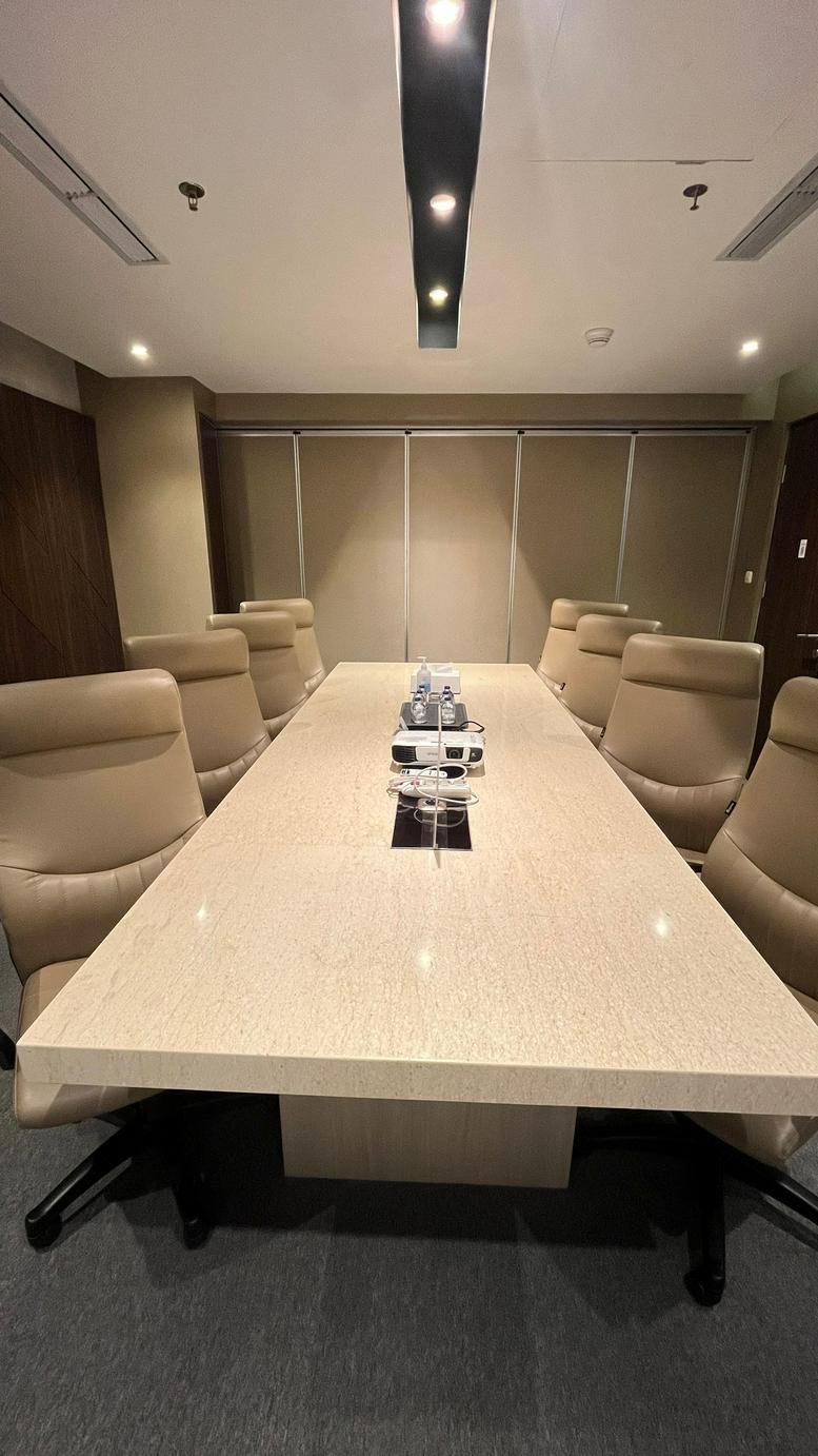 Formal boardroom at Sudirman 7. 8, Level 16 with a long cream table and tan leather chairs.