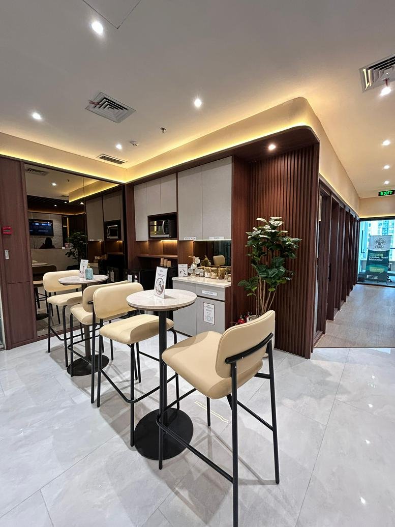 A warm communal break area at Kav. 28, Jalan Letjen S. Parman, Jakarta featuring high tables and potted plants.