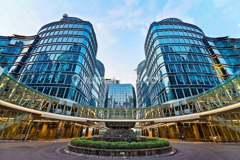 Exterior view of the curved glass facade of Landmark Pluit, Tower D6 with a grand circular driveway.