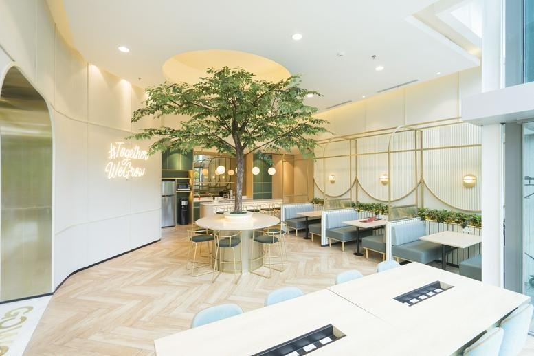 Spacious communal lounge featuring a central faux tree and wood-patterned flooring.