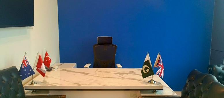 Executive office desk with a bright blue feature wall and international flags.