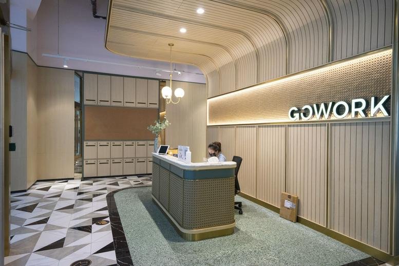 Modern reception desk at Menara Standard Chartered with a warm wood-paneled wall and branded signage.