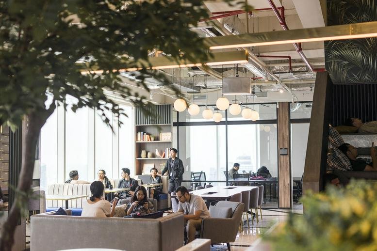 Spacious communal lounge at Millennium Centennial Center featuring a large indoor tree and floor-to-ceiling windows.