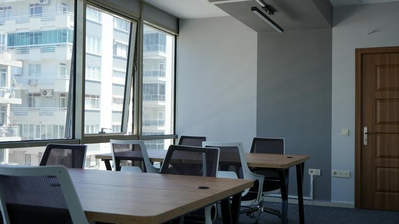 Professional interior workspace at Muratpaşa antalya featuring large windows and collaborative wooden tables.