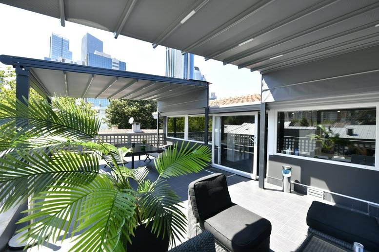 Spacious rooftop terrace at Karanfil Sokağı featuring modern seating under a large retractable awning.