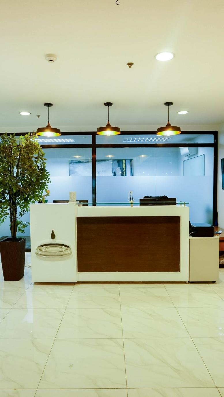 Modern reception desk at One Corporate Center with wood accents and a potted tree.
