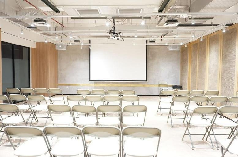 Spacious presentation hall at Park 23 Bali Mall with a large projection screen and rows of folding chairs.