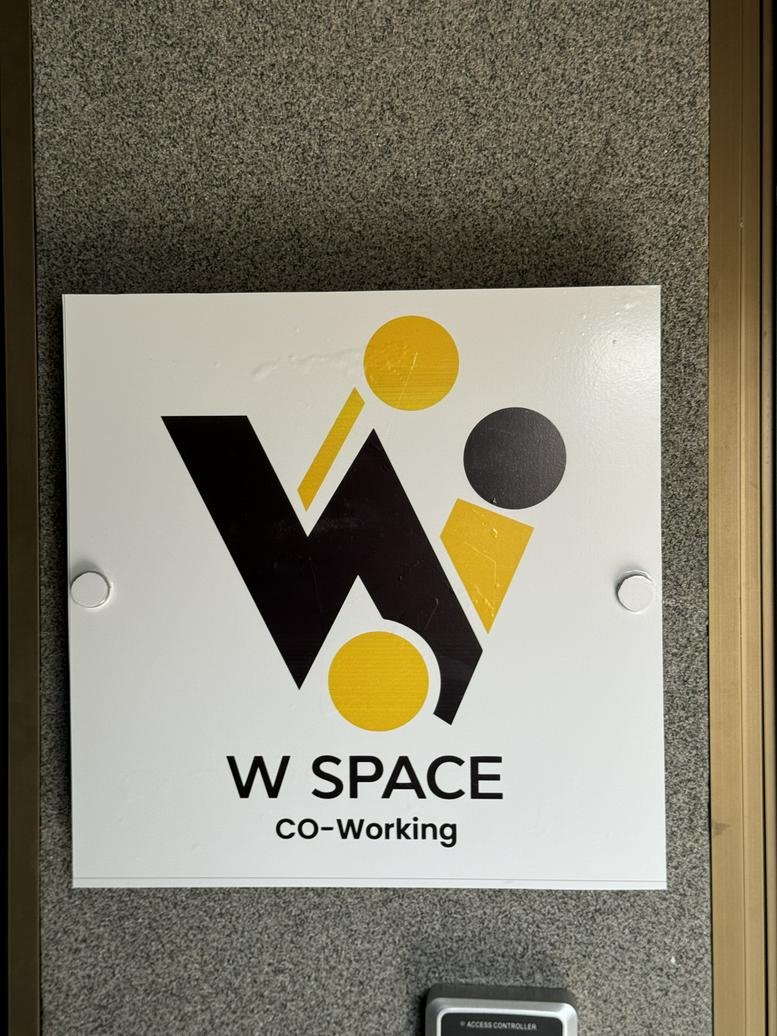 Branded signage for W Space Co-Working mounted on a textured wall.