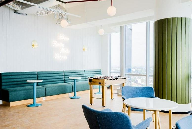Spacious breakout area at Pondok Indah Office Tower 2 with foosball, teal booths, and city views.