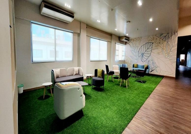 Spacious lounge at Bachrach Building II with artificial grass flooring and modern armchairs.
