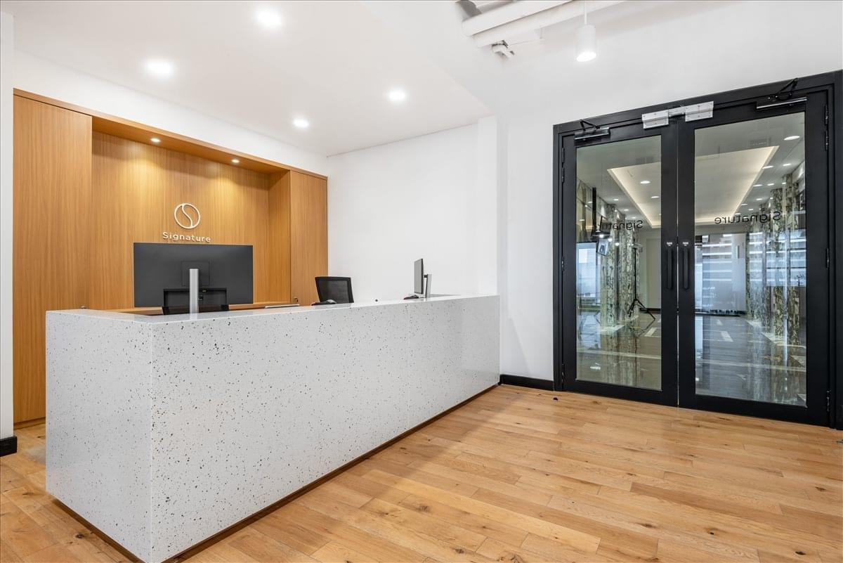 Sleek reception area with a white stone desk, wood paneling, and glass doors.