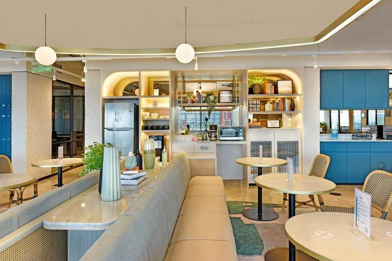 Bright breakroom featuring cafe seating, a kitchen island, and modern blue cabinetry.