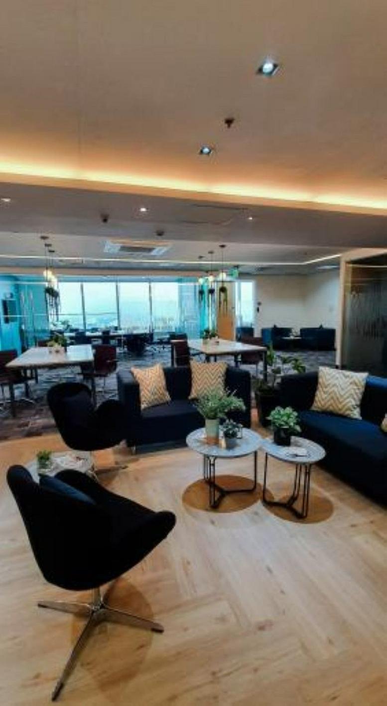 Spacious lounge at SM Aura Premier Office Tower with velvet chairs, navy sofas, and wooden floors.