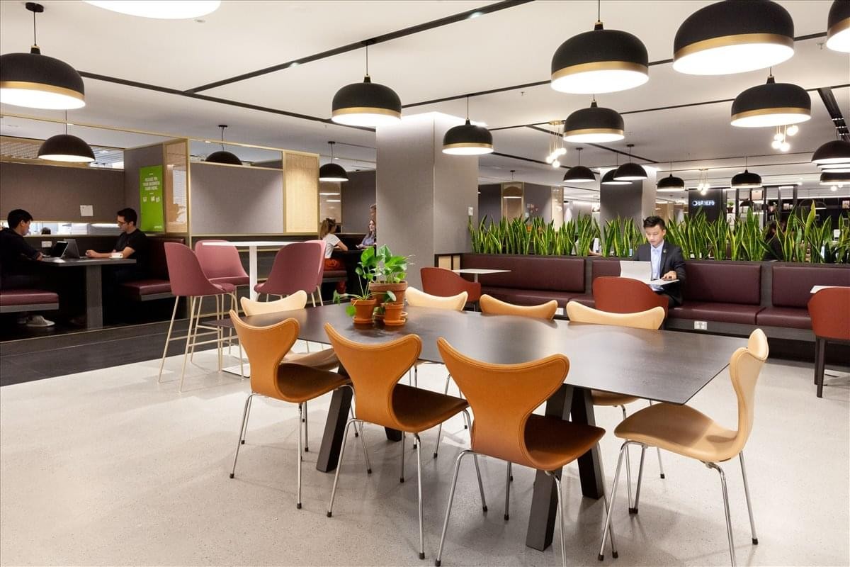 Spacious communal lounge at Stiles Enterprise Plaza featuring modern pendant lights and varied seating areas.