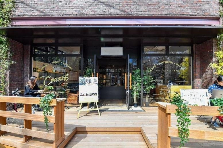 Street-level entrance of The Hive Jinnan, Tokyo, featuring dark framing, plants, and wooden decking.