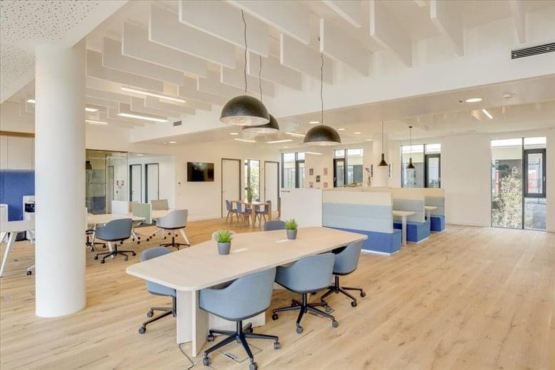 Bright, open-plan workspace at Total Building with wooden flooring and modern light fixtures.