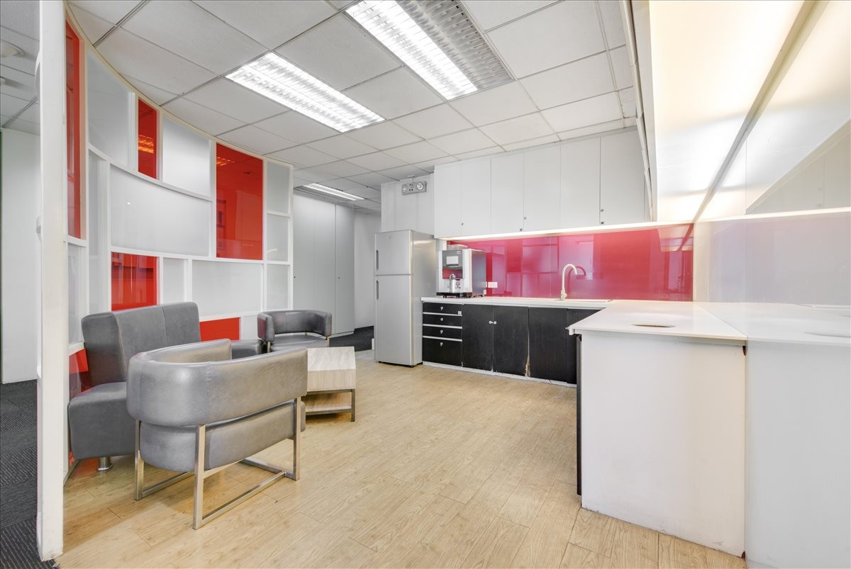 Communal kitchen and lounge area at Victoria de Makati featuring vibrant red accents and modern seating.