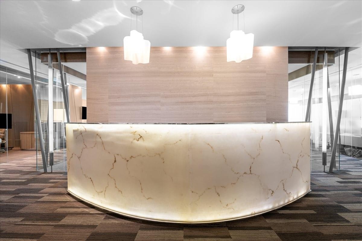 Elegant reception area featuring a curved backlit marble desk and modern pendant lighting.