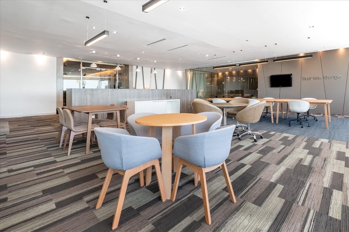 Open coworking lounge with various seating arrangements and blue upholstered armchairs.