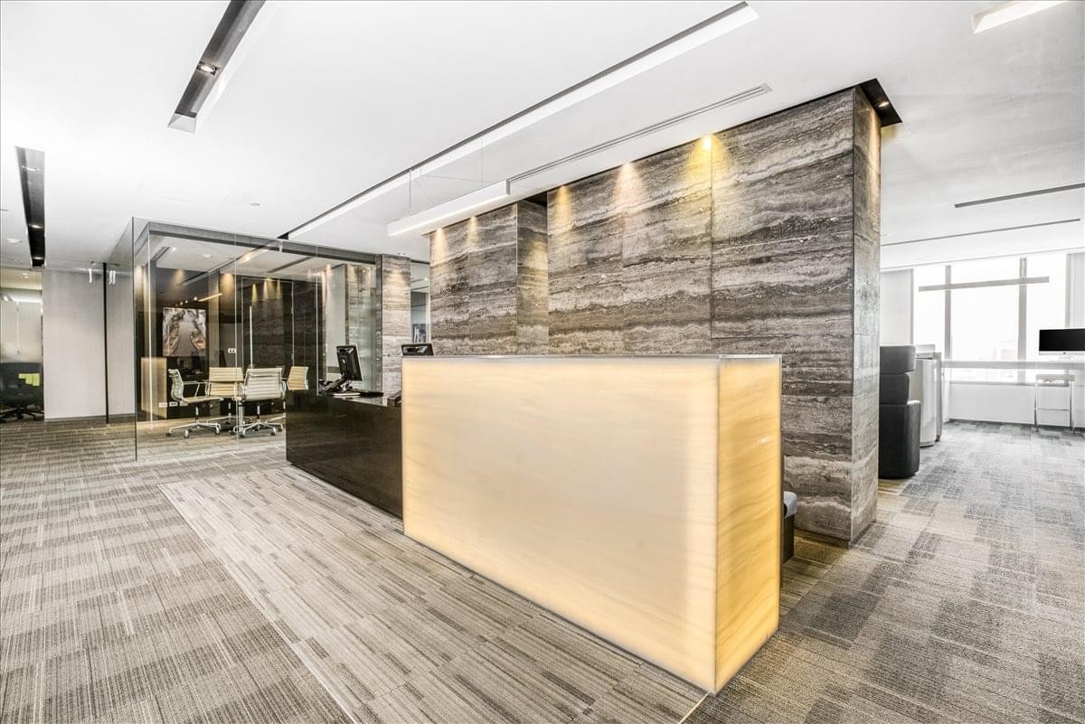 Bright reception area at 388 Sukhumvit Road with a glowing front desk and stone feature wall.