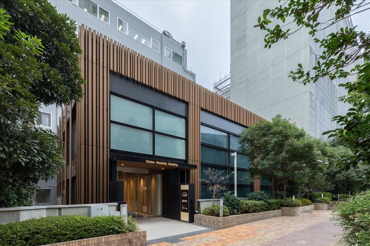 Modern exterior of the Akasaka Business Place featuring a wood-slat facade and lush greenery.