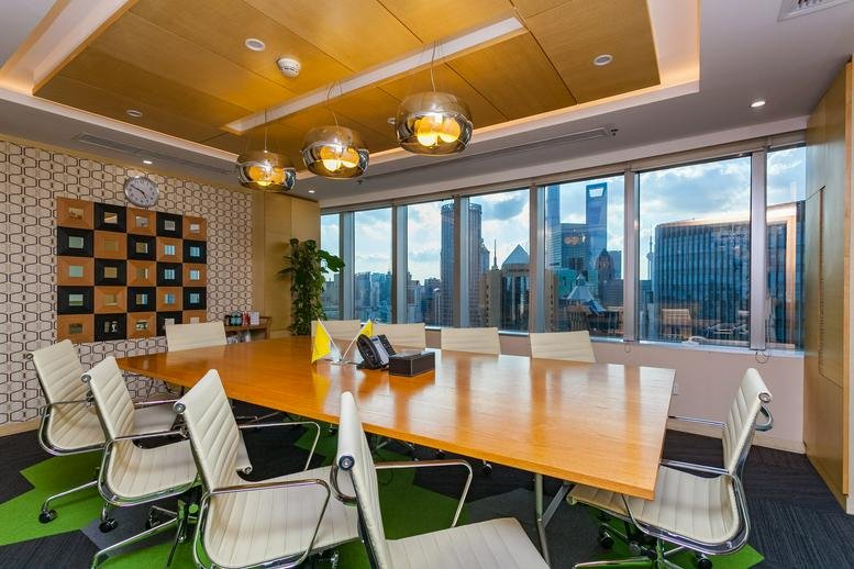 Professional boardroom with a large wood table, white leather chairs, and panoramic city views.