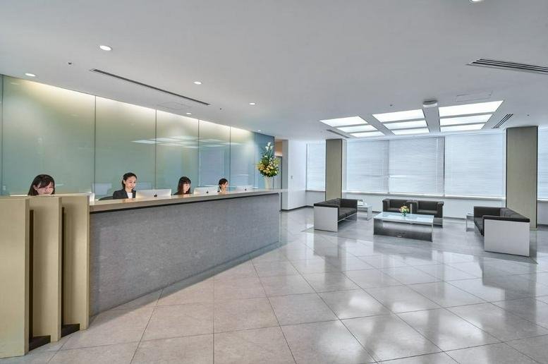 Spacious reception area with a long stone front desk, seating lounge, and natural light.