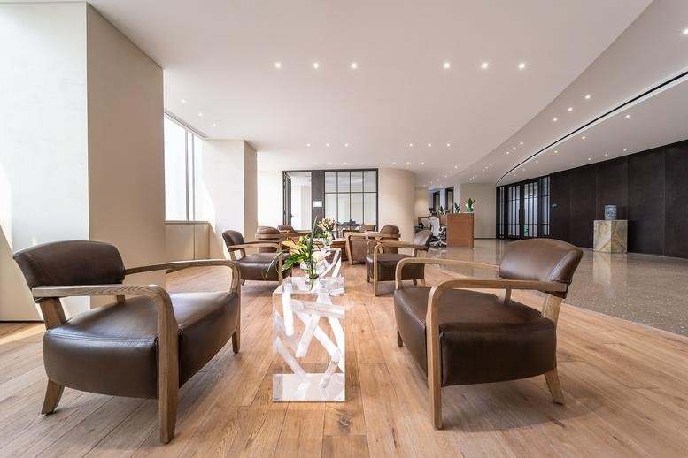 Spacious business lounge at China World Office 1 with comfortable leather seating and warm wood flooring.