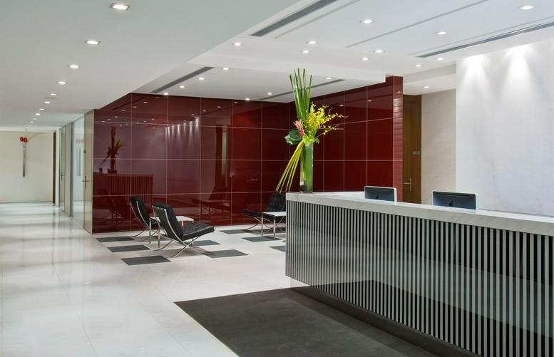 Reception area featuring a bold red feature wall, striped front desk, and modern guest seating.