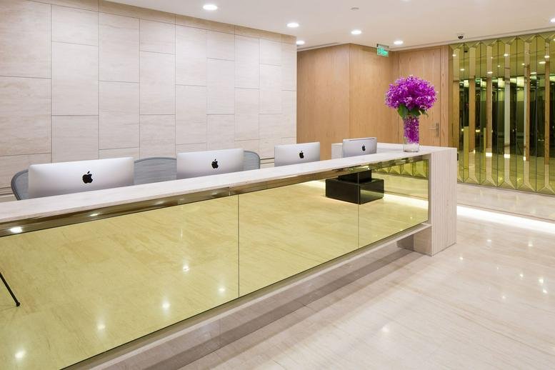Modern reception area with a reflective gold-toned front desk and purple floral arrangement.