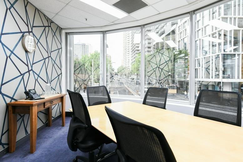 Spacious meeting room featuring a geometric feature wall and large windows with city views.