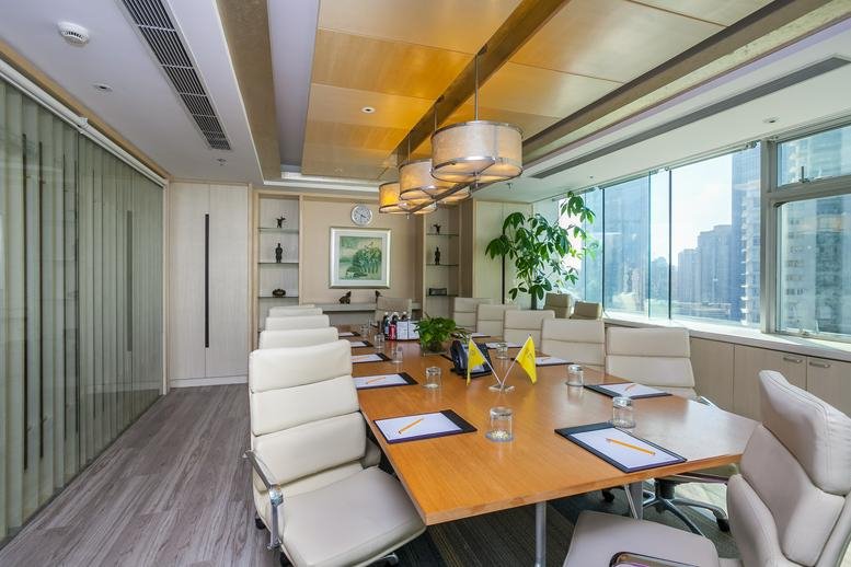 Spacious boardroom with a large wooden table, white leather chairs, and city views.