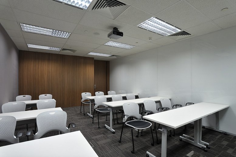 Professional training or classroom style meeting room with rows of white desks and ergonomic chairs.